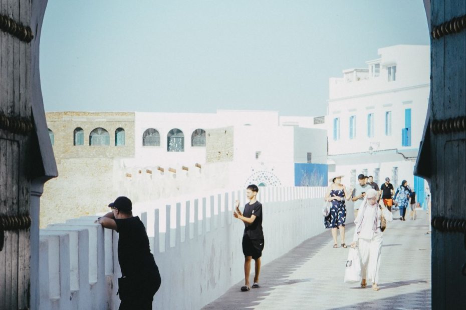 The old city walls of Asilah, Morocco, framed by an archway with people enjoying the view