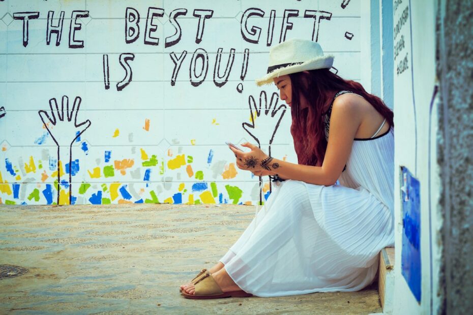 Young woman sitting on a pavement and using her smartphone in Asilah, Morocco
