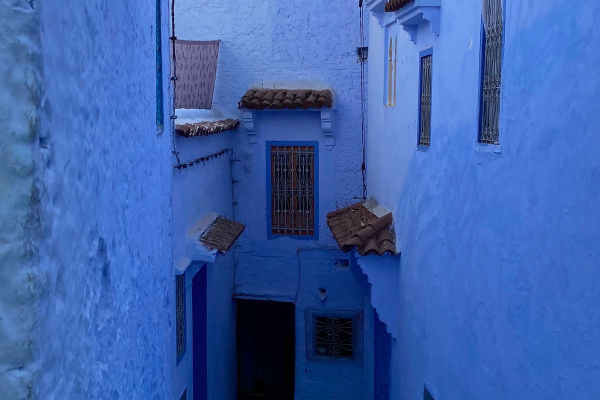 Narrow alley between blue-washed houses in the medina of Chefchaouen, Morocco