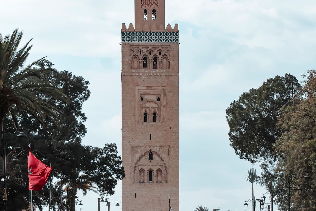 Koutoubia Mosque minaret in Marrakech, Morocco, with people walking nearby
