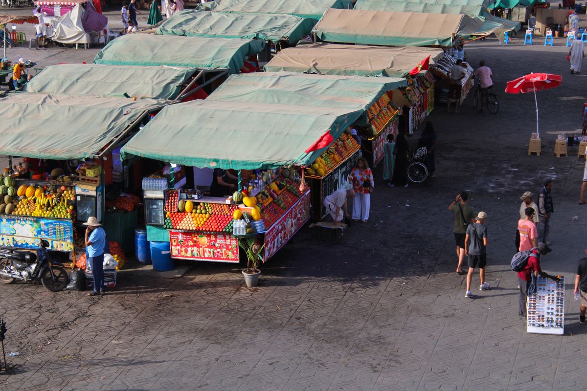Souk stalls with vendors and fresh produce in Marrakech, Morocco