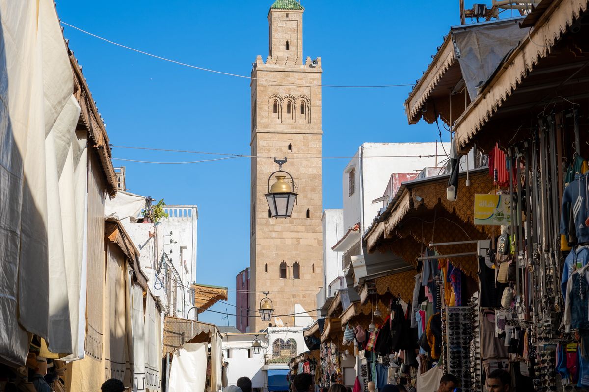 Shoppers in a busy souk in Marrakech, Morocco, with a minaret in the background