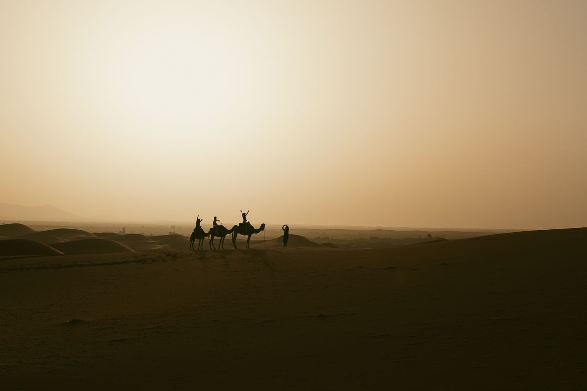 Camel caravan crossing the dunes at sunset in the Merzouga desert, Morocco