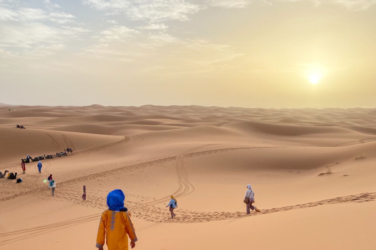 Travellers walking on the Erg Chebbi dunes near Merzouga at sunset, Morocco