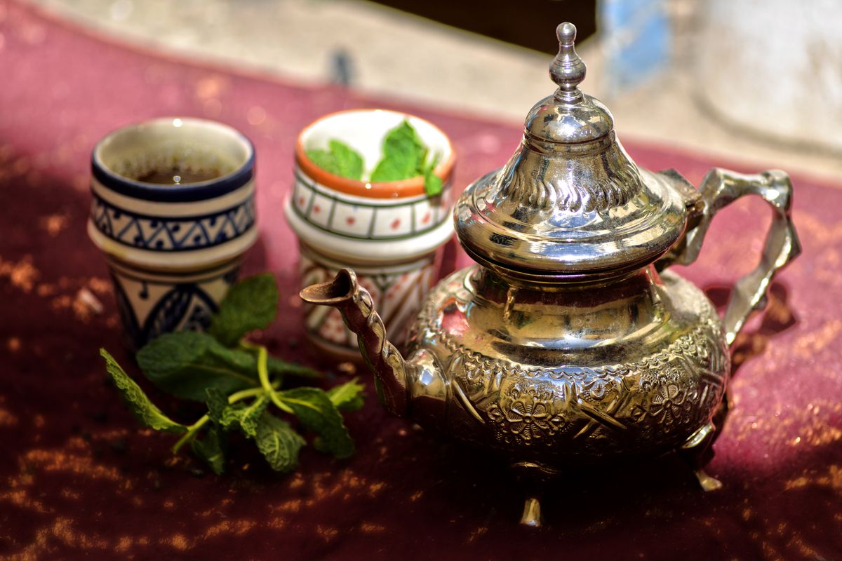 A traditional Moroccan mint tea set with a silver teapot and glasses in the sunlight in Fes, Morocco