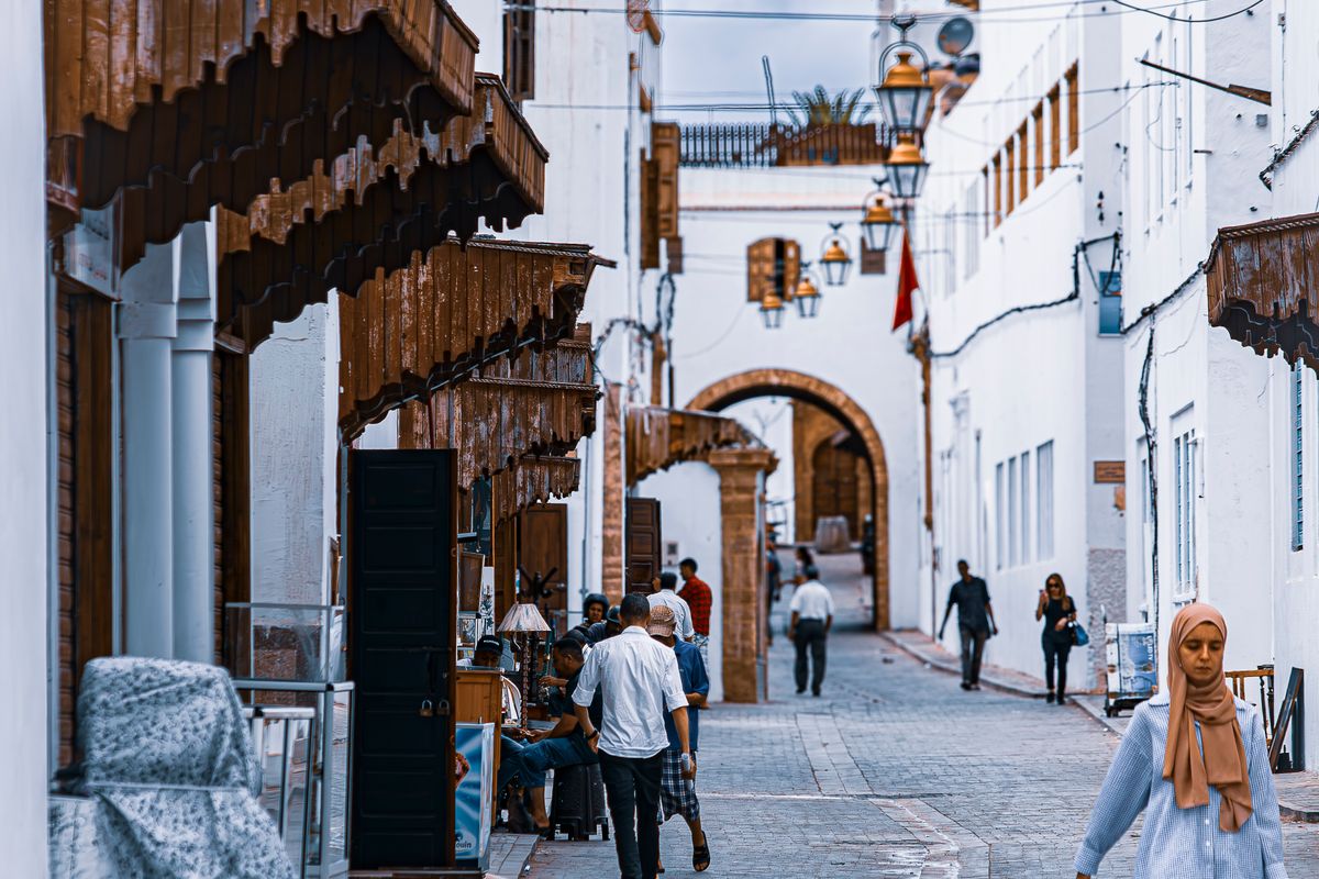A narrow alley of white buildings with street life in the medina of Rabat, Morocco