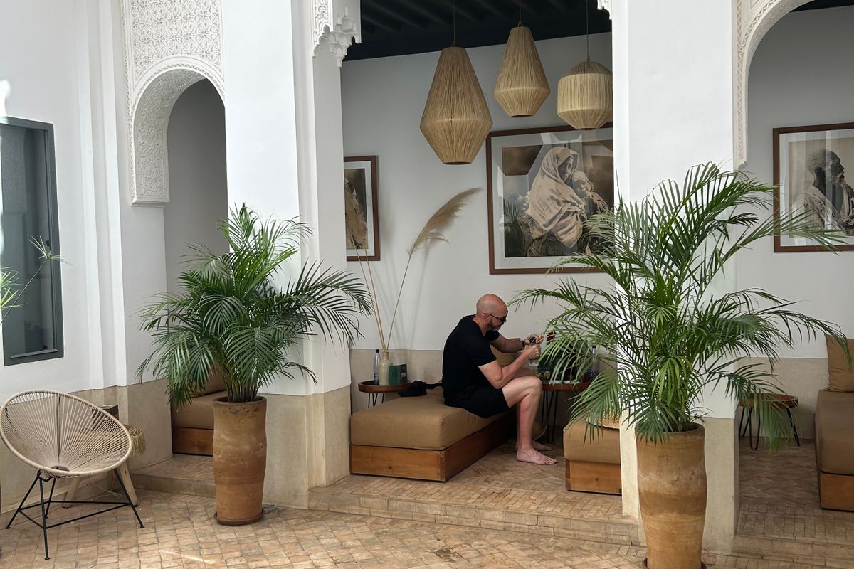 A guest relaxing in a traditional riad courtyard with a pool in Marrakech, Morocco