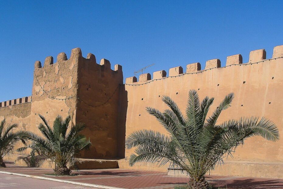 Historic earthen ramparts and palm trees of Taroudant, Morocco, under a blue sky