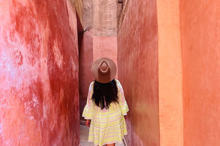A woman in a long dress walking through a colourful narrow alley in the Marrakech medina, Morocco
