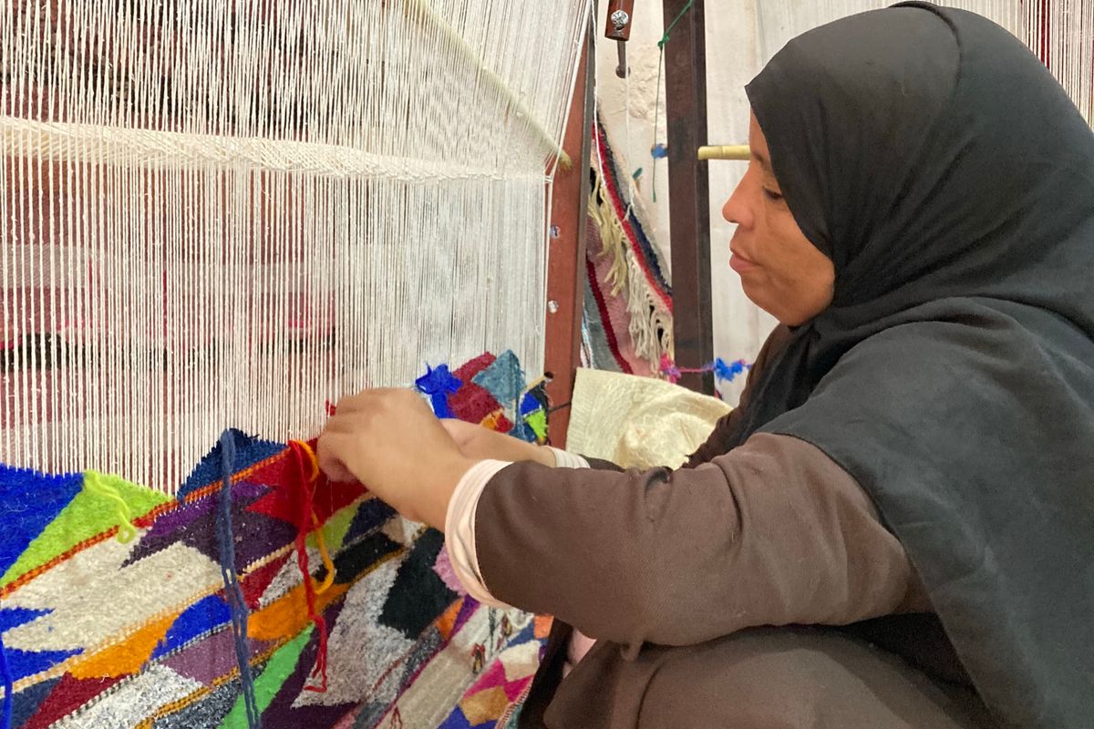 Woman weaving a colourful Moroccan rug by hand on a traditional loom in Morocco